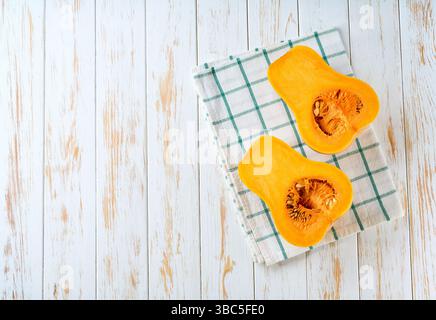 Zwei frische Hälften Butternusskürbis auf weißem Tisch, Platz für Text. Draufsicht. Stockfoto