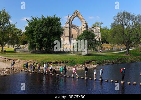 Besucher der Bolton Abbey probieren die Trittsteine über den River Wharfe aus Stockfoto