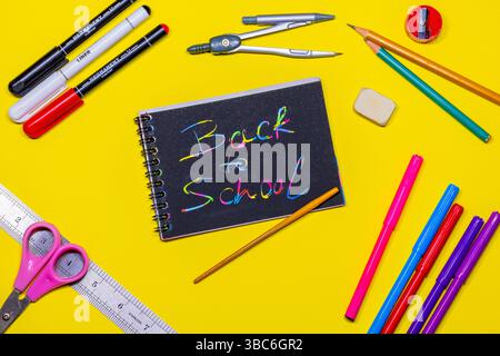 Draufsicht auf handgeschriebenes Buch „Back to School“, Schul- und Bürobedarf auf gelbem Hintergrund Stockfoto