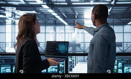 KI-Technologie, die von Softwareentwicklern für Rechenzentren verwendet wird, um Gerätediagnosen zu überprüfen. Programmierer programmieren auf einem Laptop mit künstlicher Intelligenz, Anpassen der Konfiguration der Serverfarm, Kamera B Stockfoto