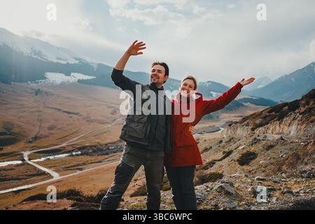 Glückliches Touristenpaar winkt im Herbst im Bergtal Stockfoto