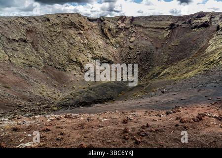 Krater des Vulkans Santa Catalina in Mancha Blanca auf Lanzarote. Die Landschaft zeigt die vulkanische Aktivität und die geologische Bildung. Die unterschiedlichen Farben von Boden und Gestein weisen auf unterschiedliche vulkanische Prozesse hin. Mancha Blanca, Kanarische Inseln, Spanien Stockfoto