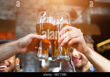 Beifall für uns. Männer trinken Bier und klirren Gläser Stockfoto