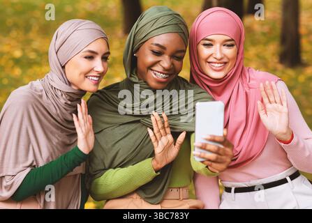 Drei Moderne Muslimische Damen Mit Smartphone Machen Video Anruf Außerhalb Stockfoto