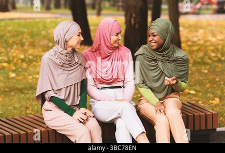 Drei Muslimische Damen In Hijab Sprechen Auf Der Bank Draußen Sitzen Stockfoto