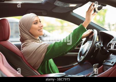Glücklich muslimische Dame fahren allein Einstellung Rückspiegel Stockfoto
