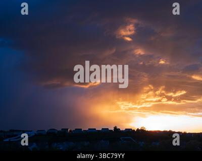 Feuriges Licht bricht bei Sonnenuntergang durch schwere Sturmwolken über Häusern in einem Wohngebiet in der Nähe von Pittsburgh, Pennsylvania. Stockfoto