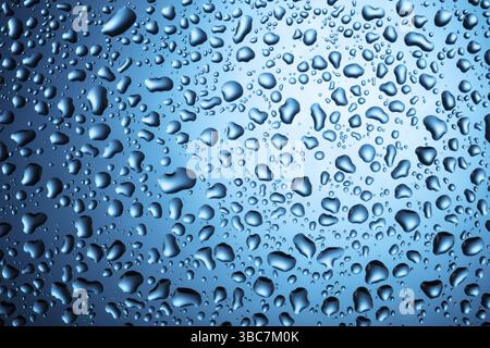 Wassertropfen auf Glas auf blauem Hintergrund Stockfoto