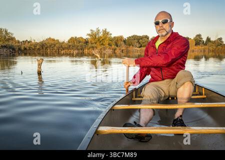 Seniorenpaddler, der auf einem ruhigen See mit dem Kanu paddeln kann, im Riverbend Ponds Natural Area, Fort Collins, Colorado Stockfoto
