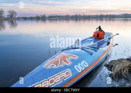 Fort Collins, CO, USA - 11. März 2018: Stand Up Paddleboard von Starboard mit wasserdichter Duffle und Paddeln auf einem ruhigen See nach Sonnenuntergang Stockfoto