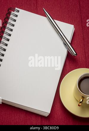 Leeres spiralförmiges Kunstskizzenbuch mit einer Tasse Kaffee gegen strukturiertes Krepppapier Stockfoto