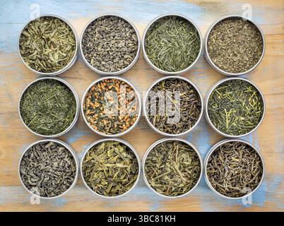 Grüner Tee Probenehmer – Draufsicht auf lose Tees in Metalldosen gegen Grunge-Holz Stockfoto