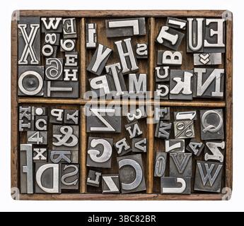 Alphabet und andere Symbole in alten Metalldruckblöcken in einer rustikalen hölzernen Satzbox Stockfoto