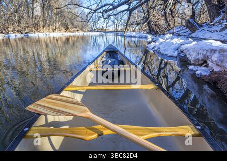Blick von einem Kanu, das auf einem Fluss paddelt, in der Winterlandschaft Stockfoto