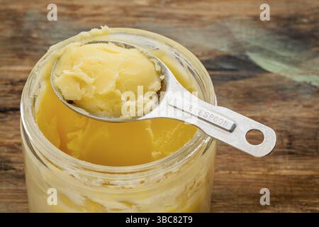 Glas und Esslöffel Ghee - geklärte Butter Stockfoto