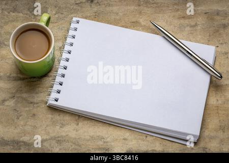 Leeres spiralförmiges Kunstskizzenbuch gegen strukturiertes Rindenpapier mit einer Tasse Kaffee Stockfoto