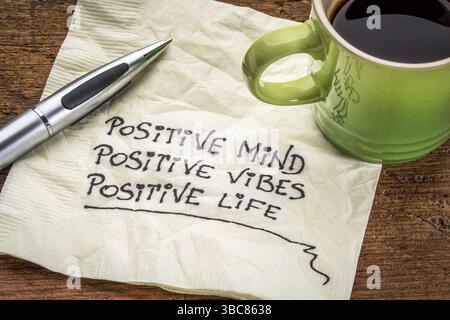 Positiver Geist, positive Vibes, positives Leben - motivierende Handschrift auf einer Serviette mit einer Tasse Kaffee Stockfoto