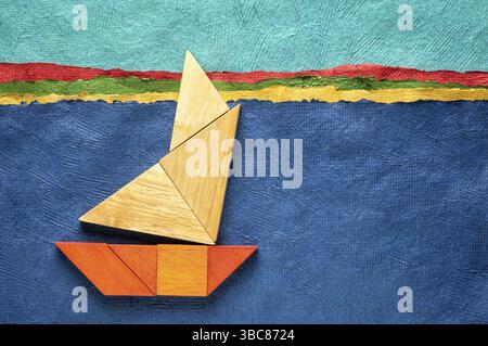 Abstraktes Bild eines Segelbootes, das aus sieben Holzstücken aus Tangram gebaut wurde, über einer Landschaft, die mit handgefertigtem strukturiertem Rindenpapier erstellt wurde, Reise- und Leerfahrt Stockfoto