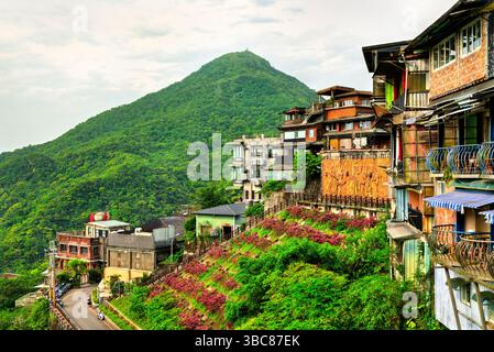 Juifen, Taiwan - 12. April 2025: Traditionelle und moderne Häuser säumen den üppigen, terrassenförmig angelegten Hügel von Jiufen in New Taipei, Taiwan. Das erhöhte Dorf bietet einen Blick auf die pulsierende Berglandschaft, mit Blumenbeeten und architektonischen Strukturen, die den Charme und den mehrschichtigen Charakter der Gegend verstärken Stockfoto