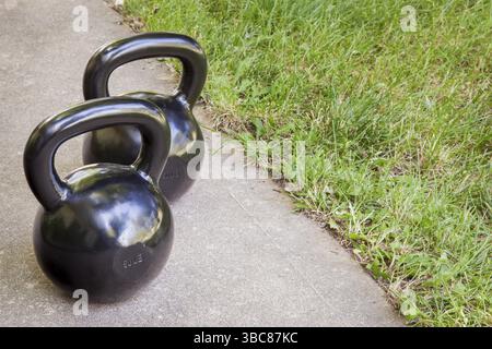 Fitnesskonzept im Hinterhof - ein paar schwere Wasserkocher auf einem Bürgersteig Stockfoto