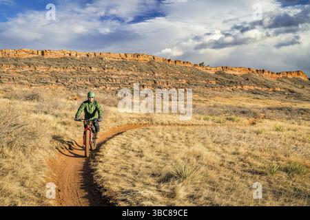 Erfahrener Radfahrer, der auf einem Fatbike auf einem Trail in den Ausläufern von Colorado (Lory State Park bei Fort Collins) unterwegs ist, einem typischen kalten, aber schneefreien Winternachher Stockfoto