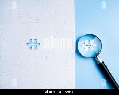 Probleme und Lösungen, Lösung, Geschäfts- und Technologiekonzept. Text „LÖSUNG“ auf dem letzten weißen Puzzleteil in Lupenlinse und Wort Stockfoto