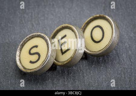 SEO Akronym (Suchmaschinenoptimierung) in alten Runde Schreibmaschine Schlüssel gegen graue Schiefer Stockfoto