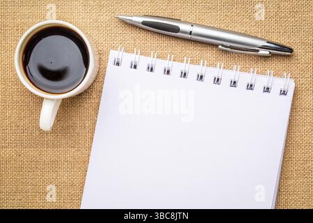 Leeres spiralförmiges Kunstskizzenbuch gegen Sackleinen mit einer Tasse Kaffee Stockfoto