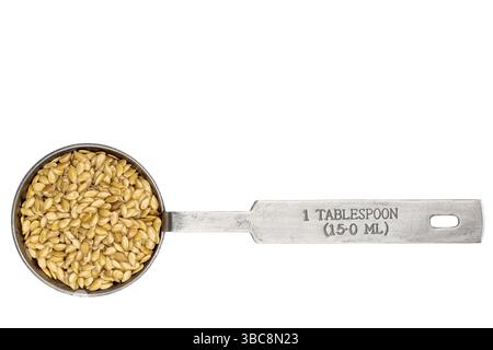 Goldene Flachssamen in einem Metallmesslöffel isoliert auf weiß Stockfoto