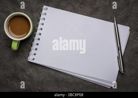 Leeres spiralförmiges Kunstskizzenbuch gegen strukturiertes Rindenpapier mit einer Tasse Kaffee Stockfoto