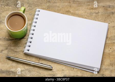 Leeres spiralförmiges Kunstskizzenbuch gegen strukturiertes Rindenpapier mit einer Tasse Kaffee Stockfoto