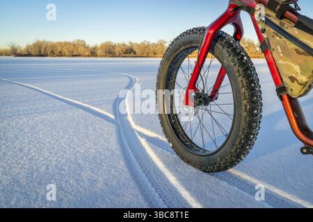 Fette Fahrräder, Fußabdrücke und Schatten auf einem gefrorenen See im Norden von Colorado Stockfoto