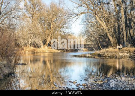 Fort Collins, CO, USA - 10. März 2018: Ein junges Paar genießt einen warmen Frühjahrsnachmittag am Ufer des Cache la Poudre River Stockfoto