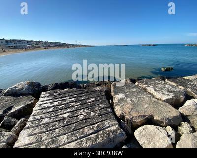 Ruhiges, klares Meerwasser, das an einem sonnigen Tag am Strand von Francavilla al Mare in den Abruzzen, Italien, sanft gegen die Wellenbrecher plätschert Stockfoto