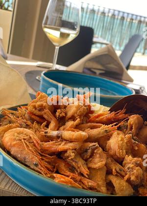 Knusprige goldene Garnelenplatte mit gekühltem Weißwein im sizilianischen Restaurant am Wasser in Siracusa Stockfoto