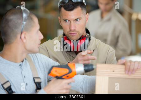 Ein Lehrling bohrt ein Loch in ein Holzbrett Stockfoto