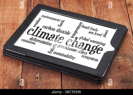 Klimawandelwortwolke auf einem digitalen Tablet gegen rustikales Scheunenholz Stockfoto