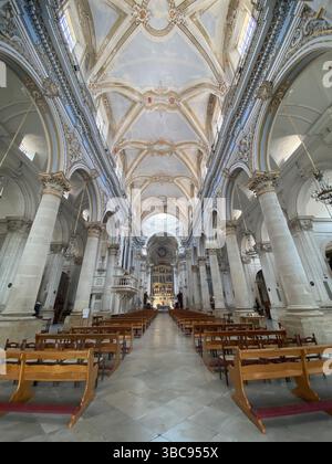 Weitwinkelansicht des barocken Innenraums der Chiesa di San Pietro in Modica, Sizilien, Italien, mit dem Schiff, den Bänken und der verzierten Decke Stockfoto