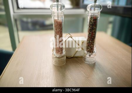 Salz- und Pfeffermühlen auf einem Holztisch und Papierservietten Stockfoto