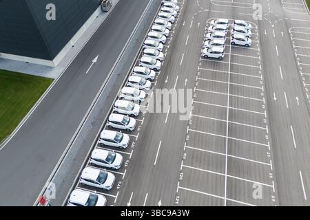 Flotte von Merchandising-Fahrzeugen, die neben einem Logistikzentrum geparkt sind. Luftaufnahme. Stockfoto