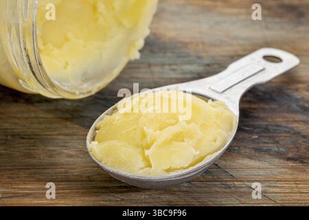 Glas und Esslöffel Ghee - geklärte Butter Stockfoto