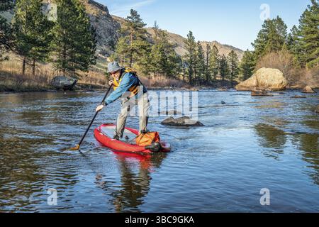 Aufblasbares Stand Up Paddleboard auf einem Bergfluss - Poudre River in Colorado in Frühlingslandschaft mit niedrigem Wasserfluss Stockfoto