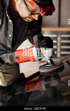 Mann in einem Garagenwagen mit Poliermaschine. Stockfoto