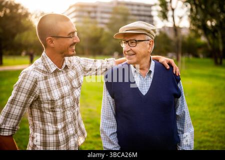 Porträt von glücklichem Großvater und Enkel im Park. Sie sind sehr umgangssprachlich. Stockfoto