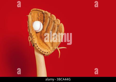 Hand in Leder Baseballhandschuh hält weißen Baseball auf rot. Hochwertige Fotos. Gewinner. Kopierbereich. Werbung Stockfoto