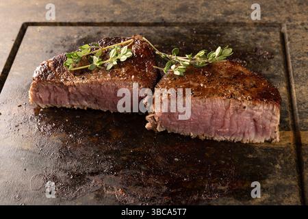 Brodelnde mittelseltene Filet Mignon Steaks mit Thymian auf heißem Stein Stockfoto