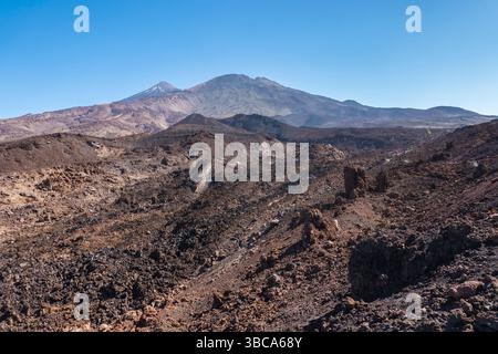 Winterblick auf den farbenfrohen Vulkan Pico del Teide mit Schneepunkten vom Wanderweg Samara. Berge und Lavafelder vor blauem Himmel. El Teide National Stockfoto