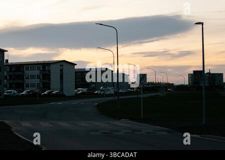 Akranes, Island - 16. Mai 2025: Urbane Szene von Akranes, Island in der Abenddämmerung mit Wohnhäusern, Straßenlaternen und Wolken. Stockfoto