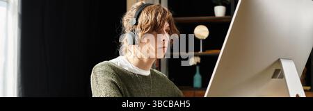 Ein junger Student absolviert zu Hause konzentriertes Studium, eingetaucht in das Online-Lernen. Stockfoto