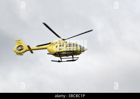 Stockholm, Schweden - 6. April 2025: Ein gelber und grüner medizinischer Hubschrauber mit dem Wort Ambulance an der Seite. Es fliegt am Himmel. Stockfoto